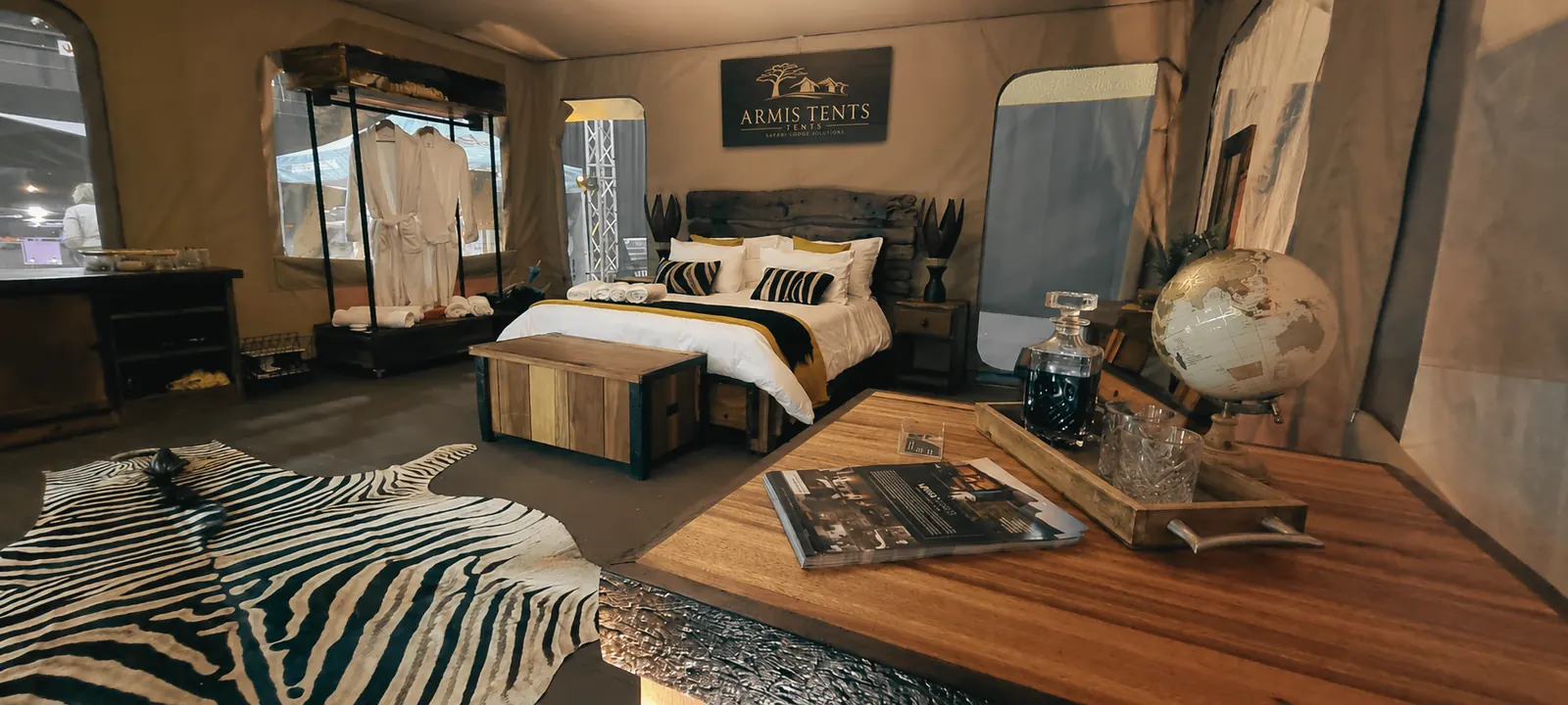 Safari tent interior with king bed, zebra rug and timber furniture