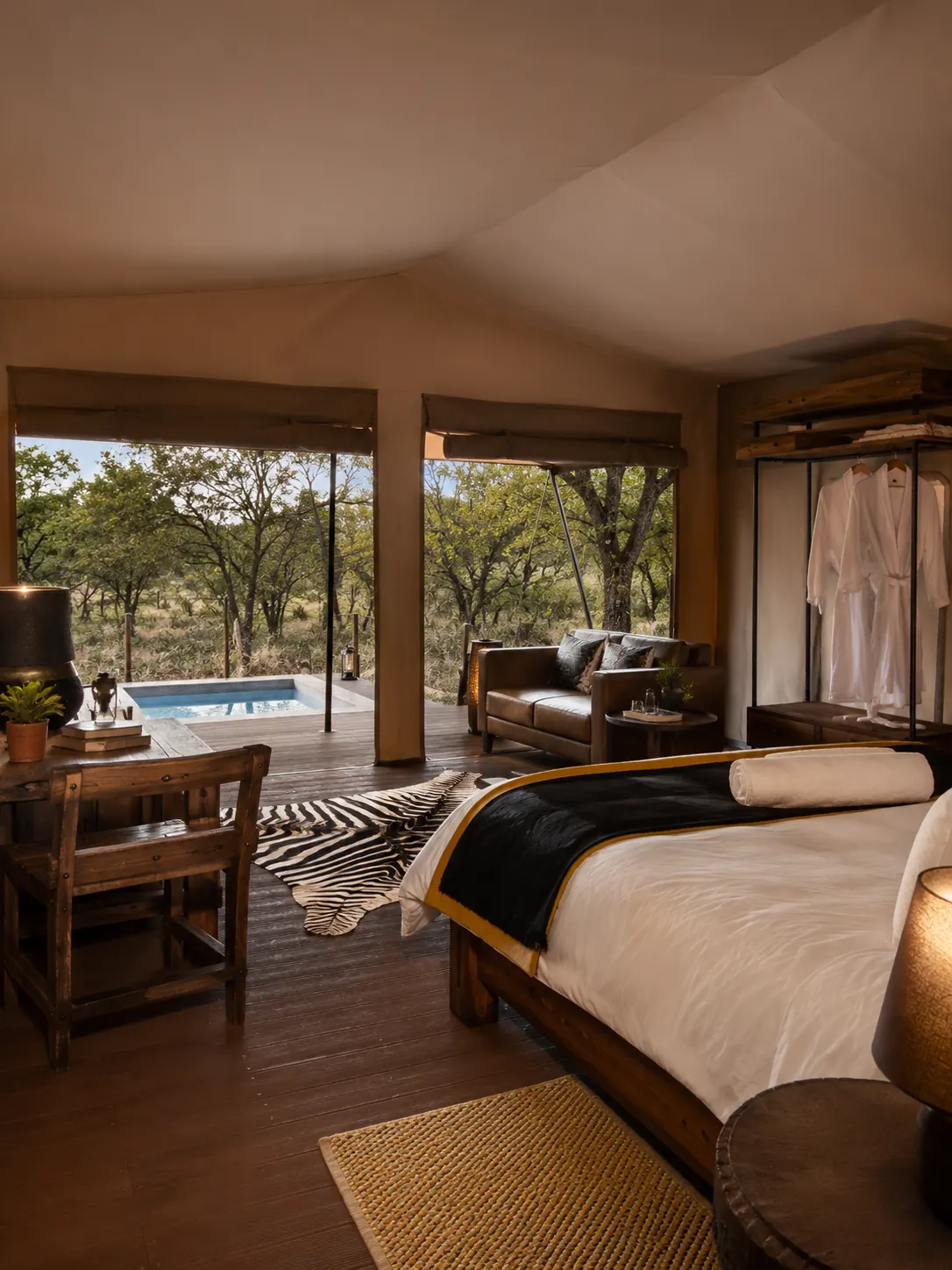 View from a safari tent bed across the deck to a plunge pool and the bush